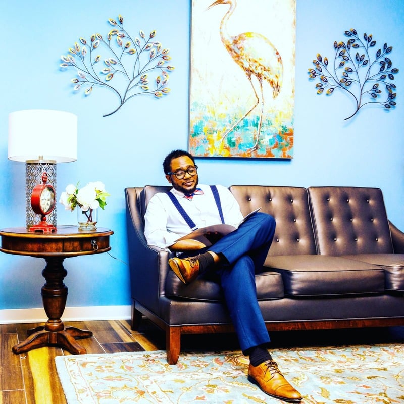 Stéphane Ikoué seated with a book in his creative space